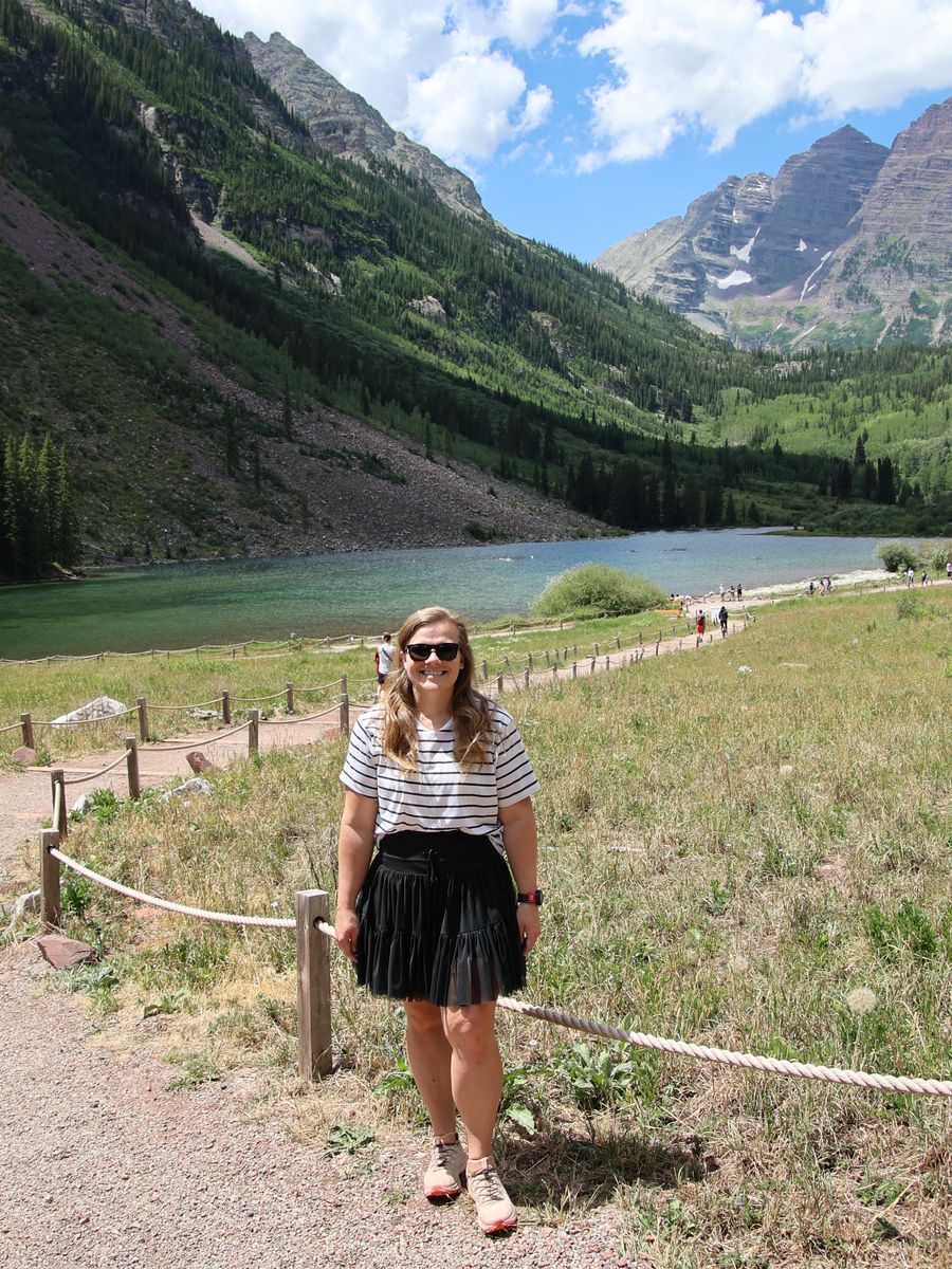 Hanna Page standing lakeside below the Maroon Bells in the Colorado Rockies