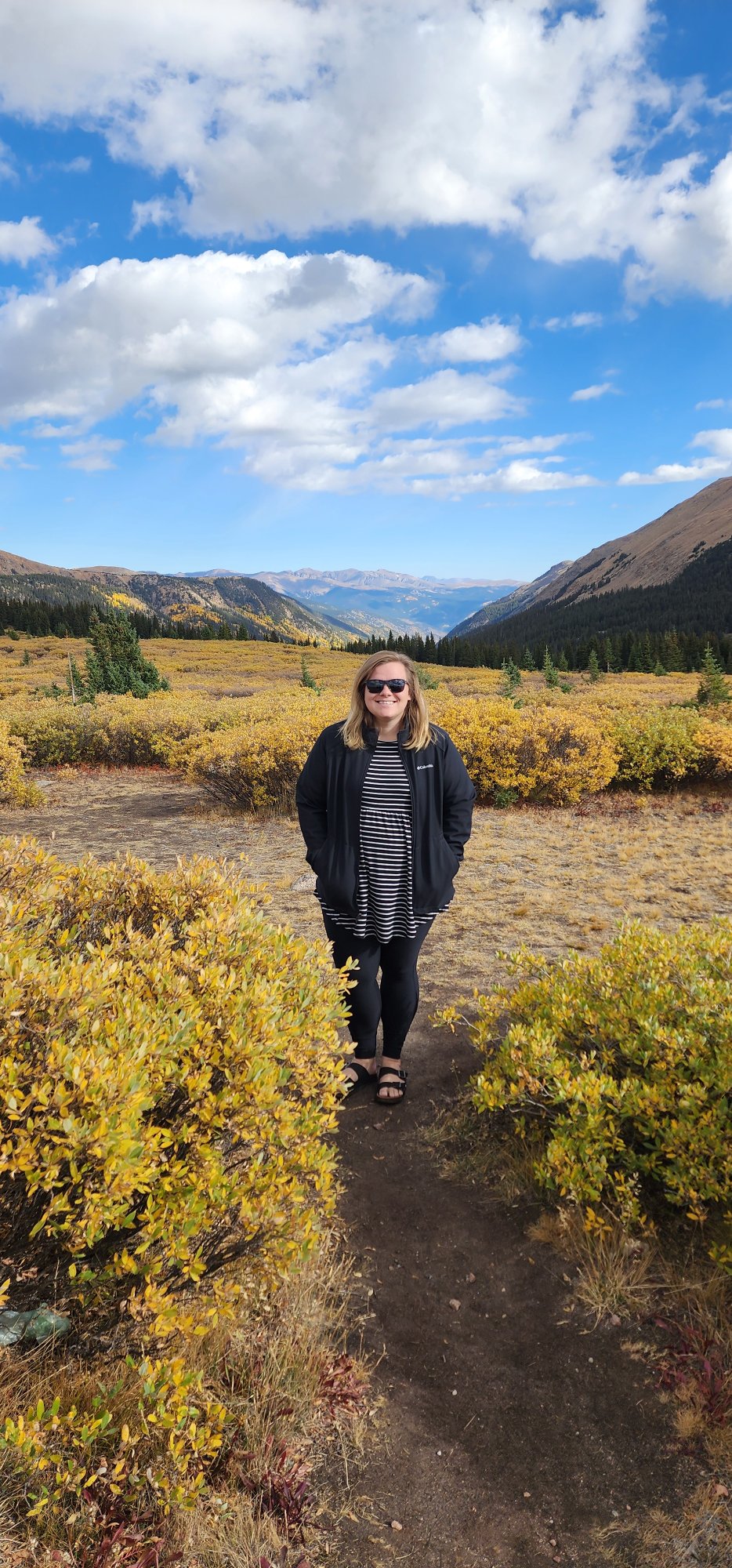 Hanna Page on a Colorado mountain trail surrounded by fall foliage