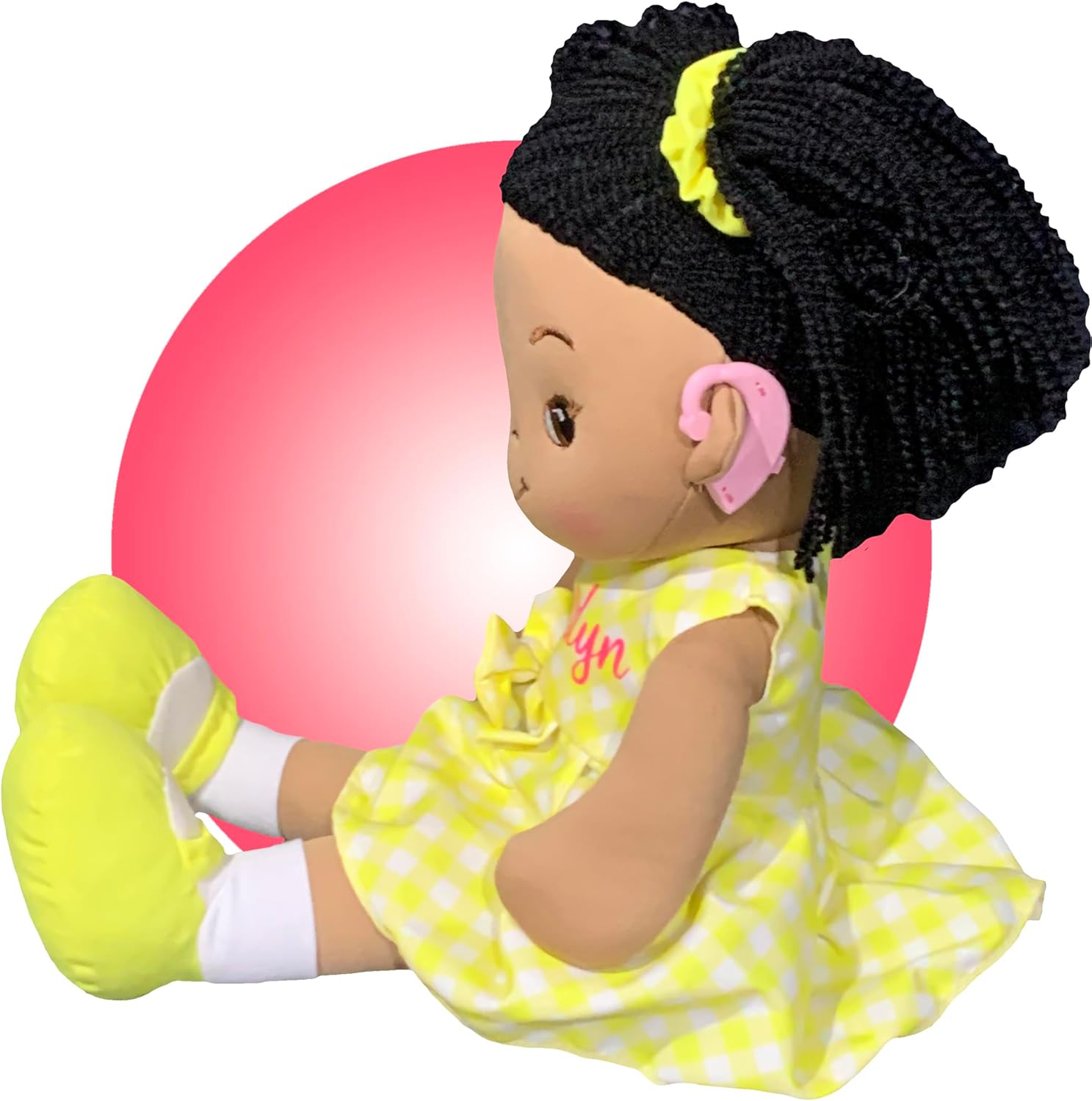 Doll wearing pink hearing aids in a yellow gingham dress